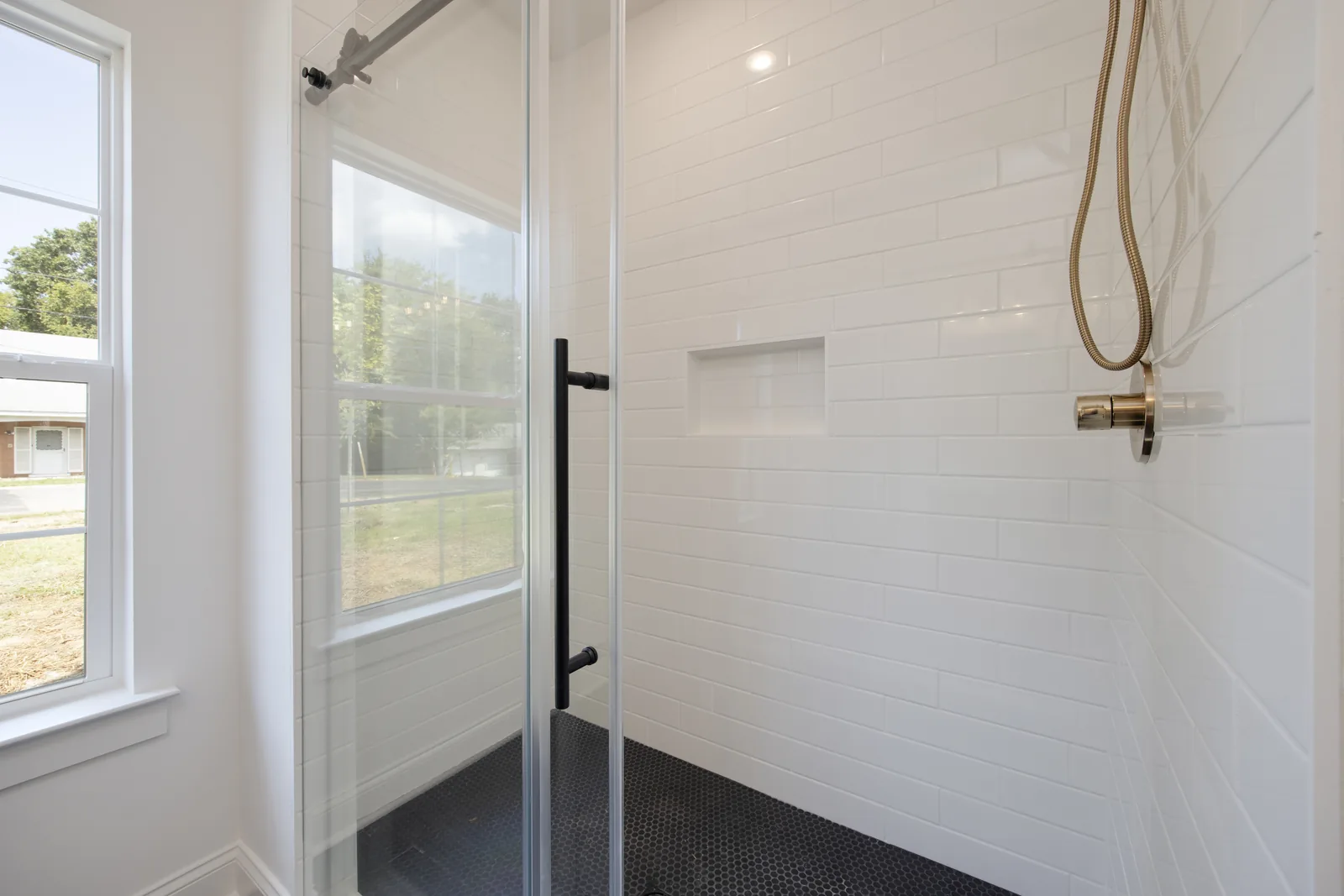 Walk-in shower with white subway tile and brass fixtures