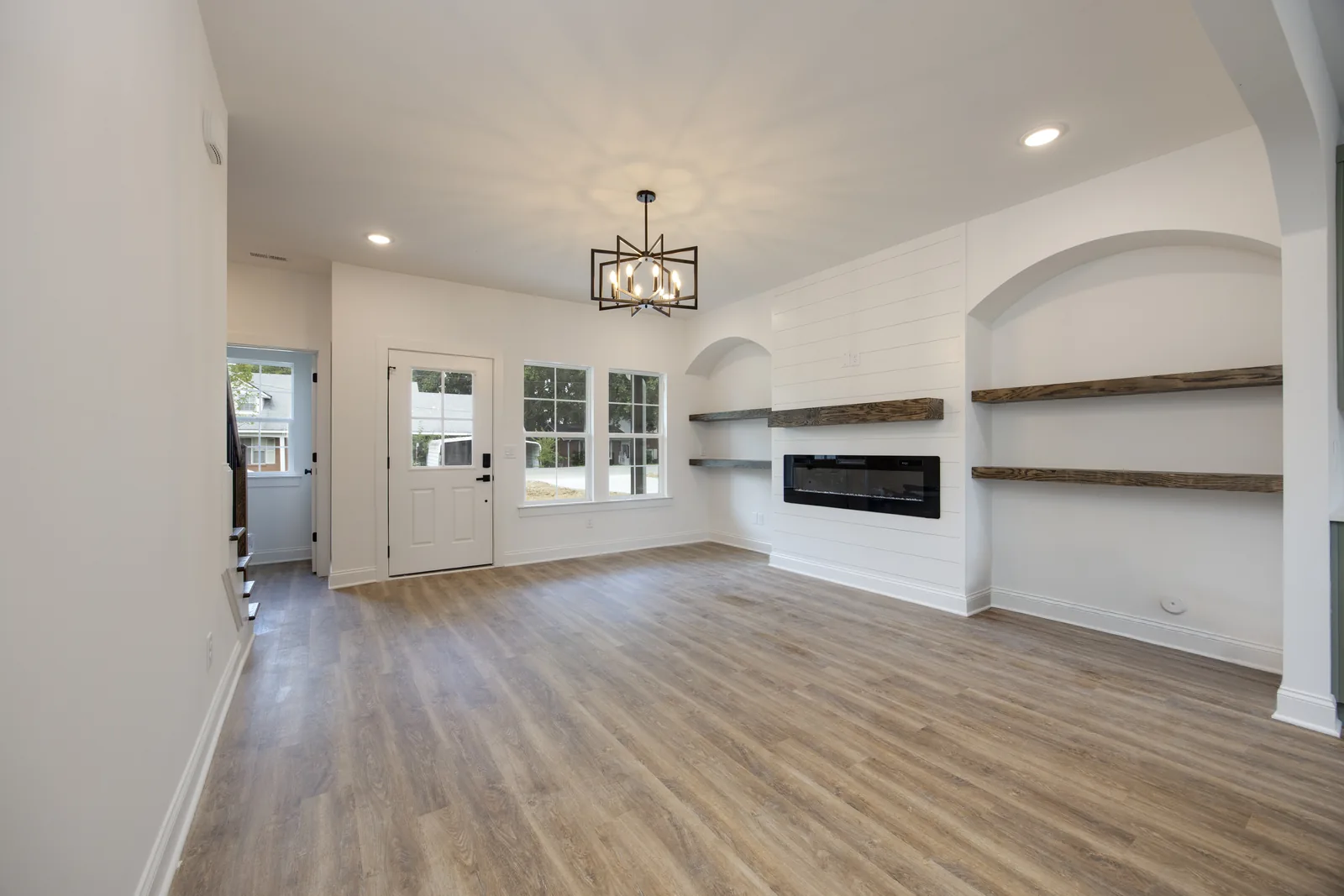 Living room with a linear fireplace, floating shelves, and arched display niches