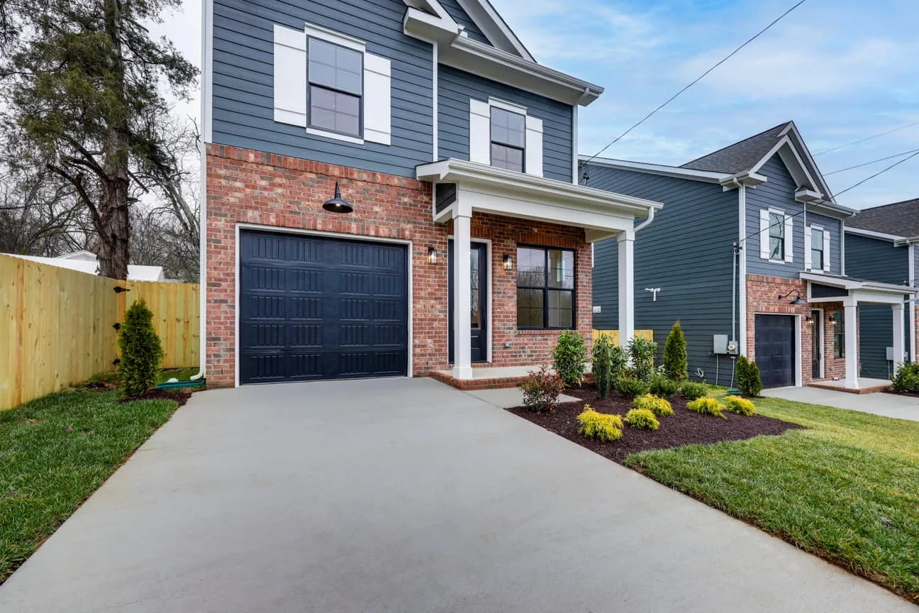 Front of 413 Cumberland Ave — blue siding with a brick-wrapped garage bay and fresh landscaping