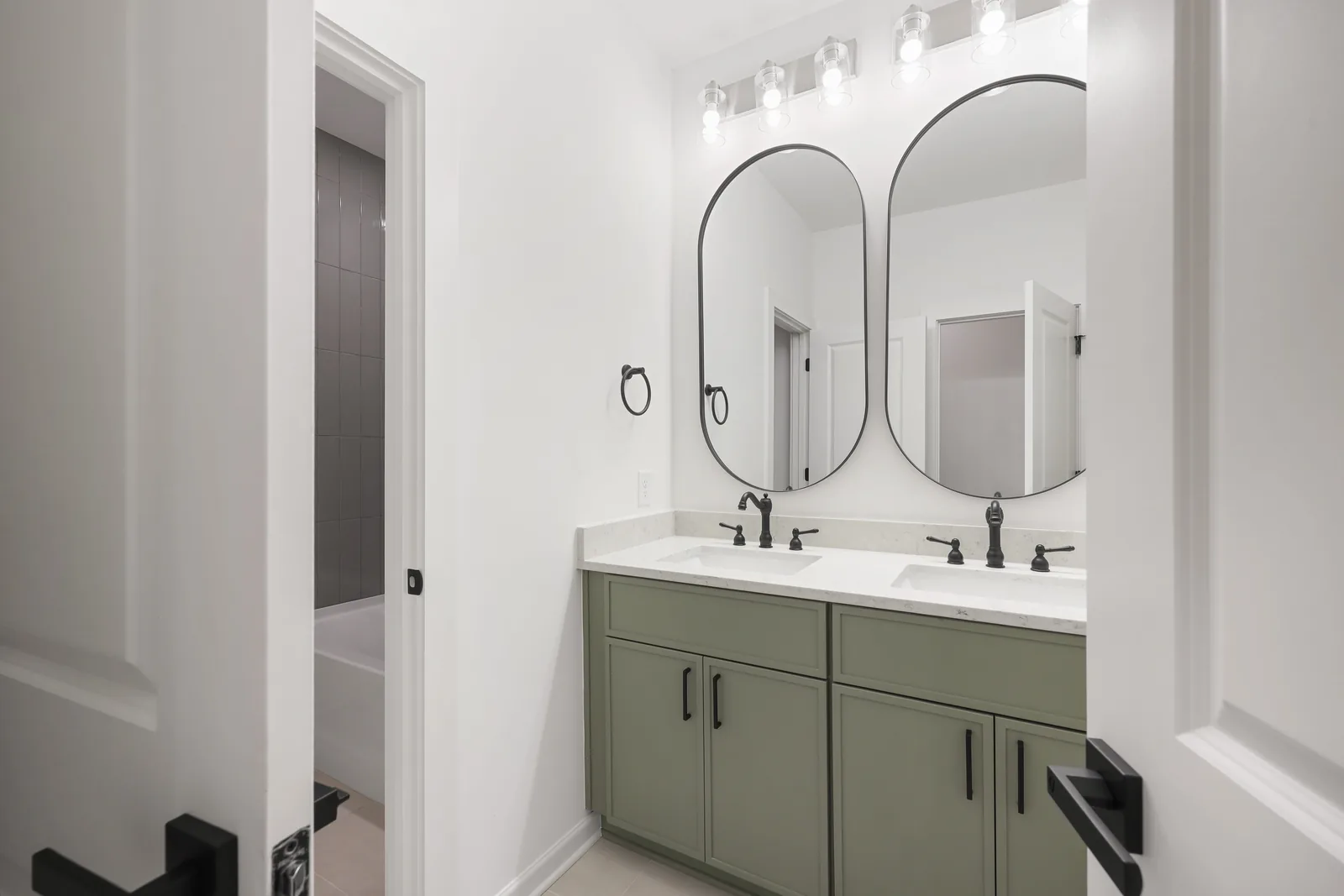 Bathroom vanity with sage-green cabinetry and double mirrors