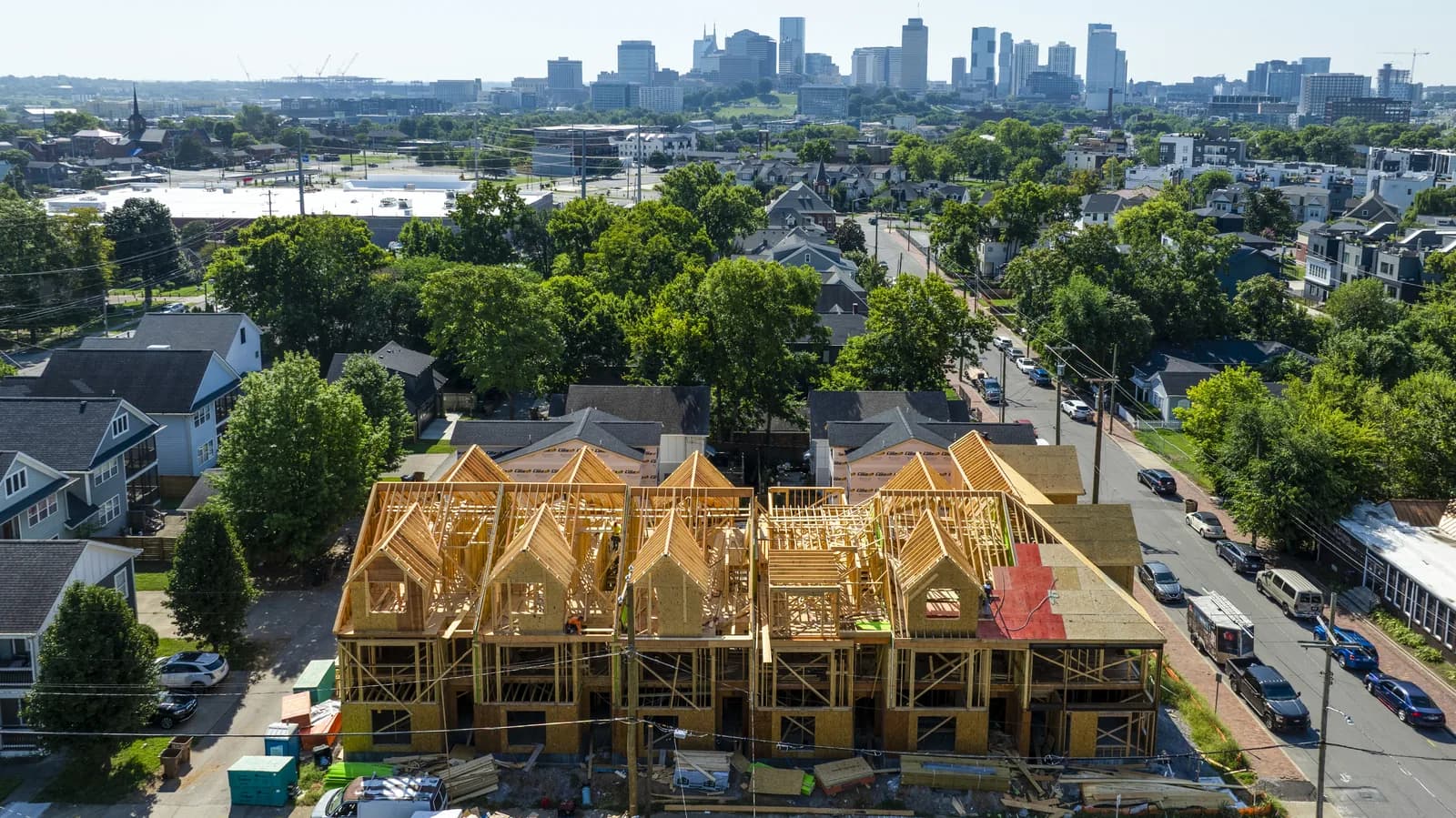 Aerial of the eight-townhome block at 909 Cheatham Pl during framing, downtown Nashville on the horizon