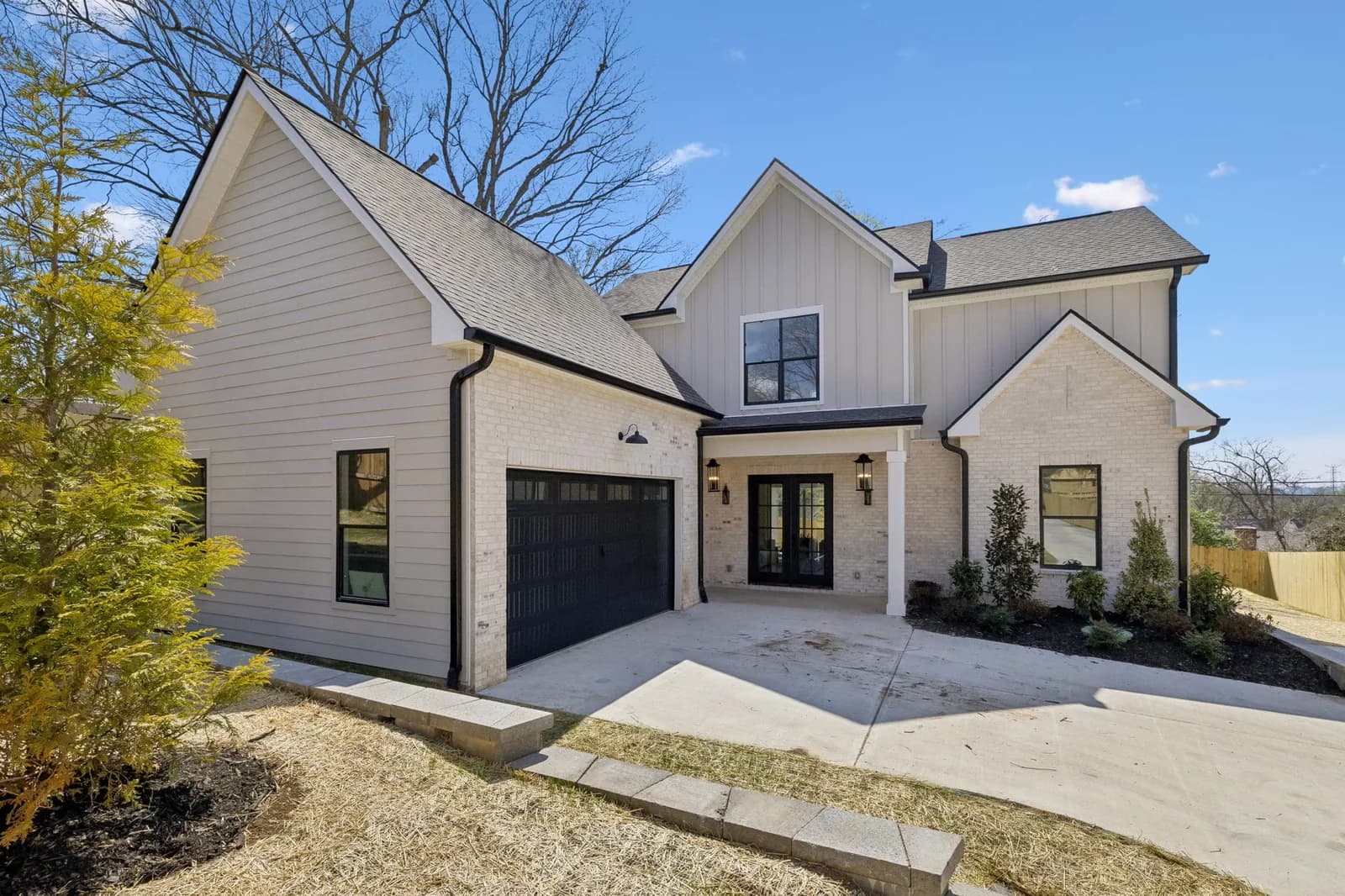 Front elevation of 621B Westboro Dr — white board-and-batten gables, a black garage door, and boxwoods along the entry walk
