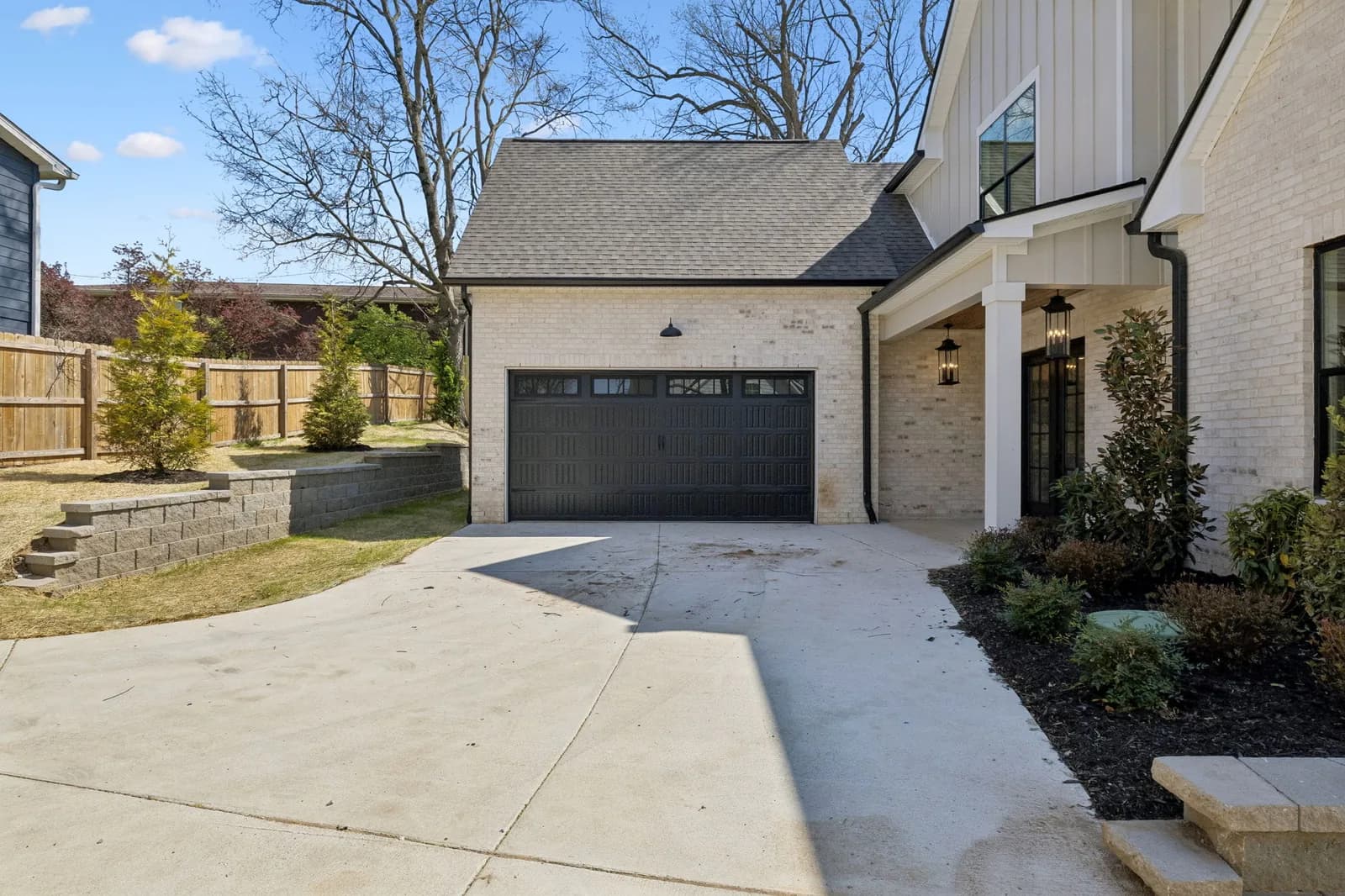 Concrete drive court and garage entry with a stone retaining wall and new plantings