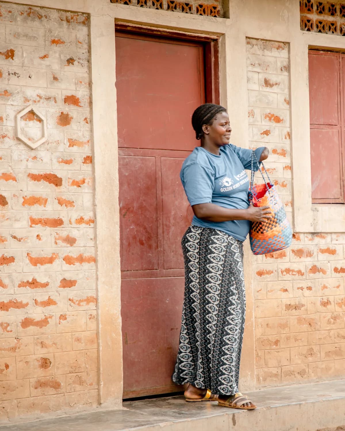 Margaret standing on the front porch of her new brick home in Northern Uganda