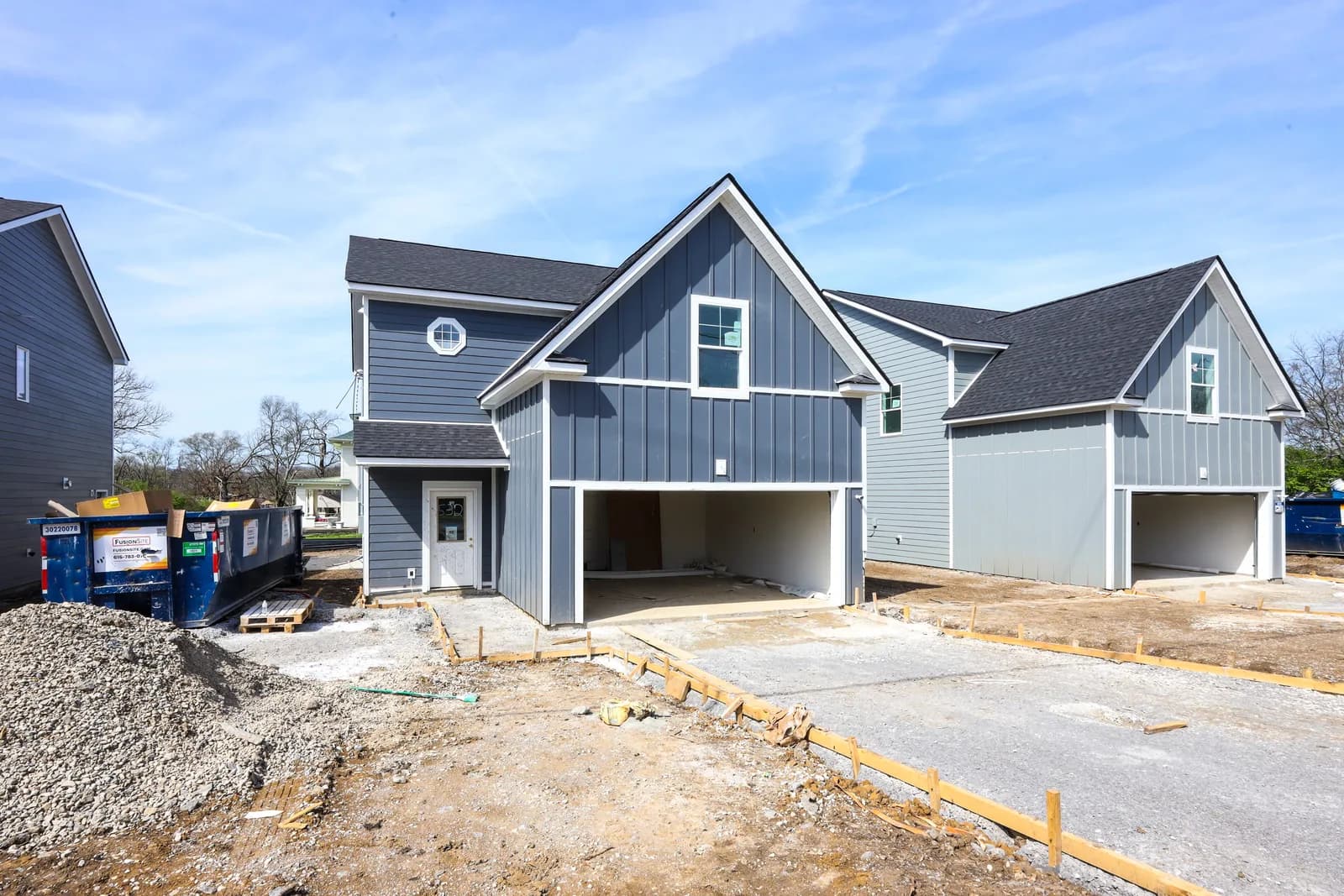 Three Forest Park homes in a row mid-construction, siding hung and drives still gravel