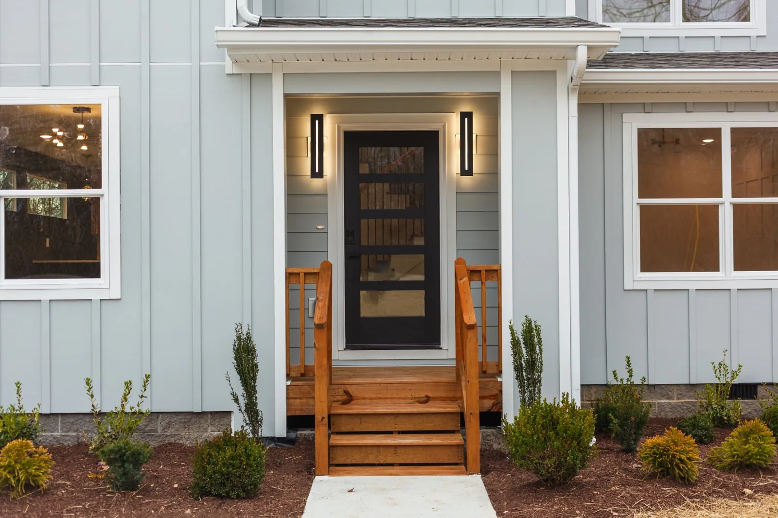 Front entry of 809 Swinging Bridge Rd — cedar porch rails against pale blue board-and-batten siding