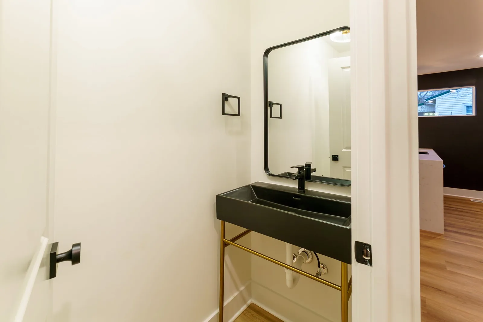 Powder room with a black sink basin on a brass stand