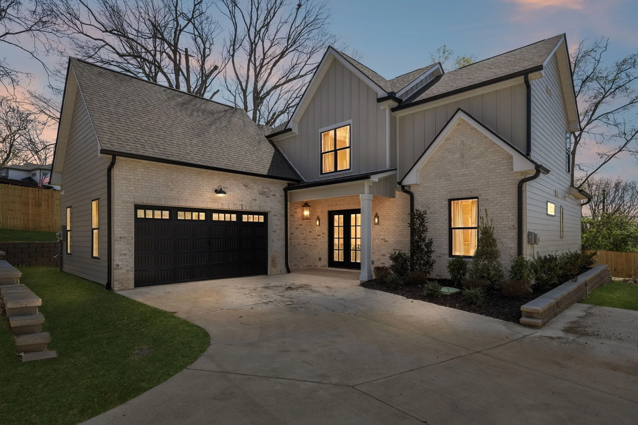 May Construction's Westboro home on a sloped corner lot in Nashville, where a stone retaining wall holds the lawn above the drive court.